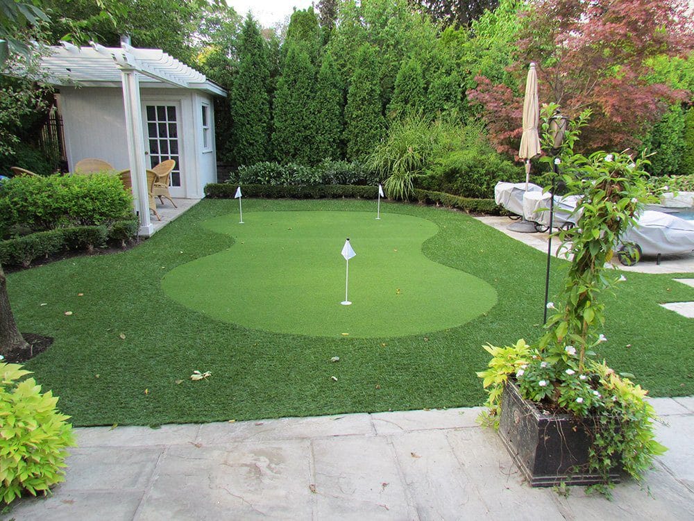 a lazy eight shaped golf green surrounded with landscape grass by pool